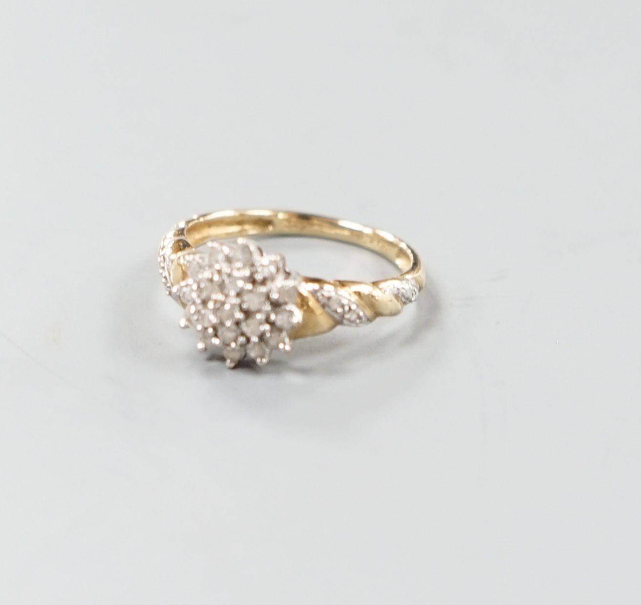 A modern 9ct gold and diamond cluster ring, with diamond chip set shoulders, size P, gross weight 2.5 grams.